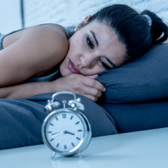 A female laying on the bed showing a sleep disorder