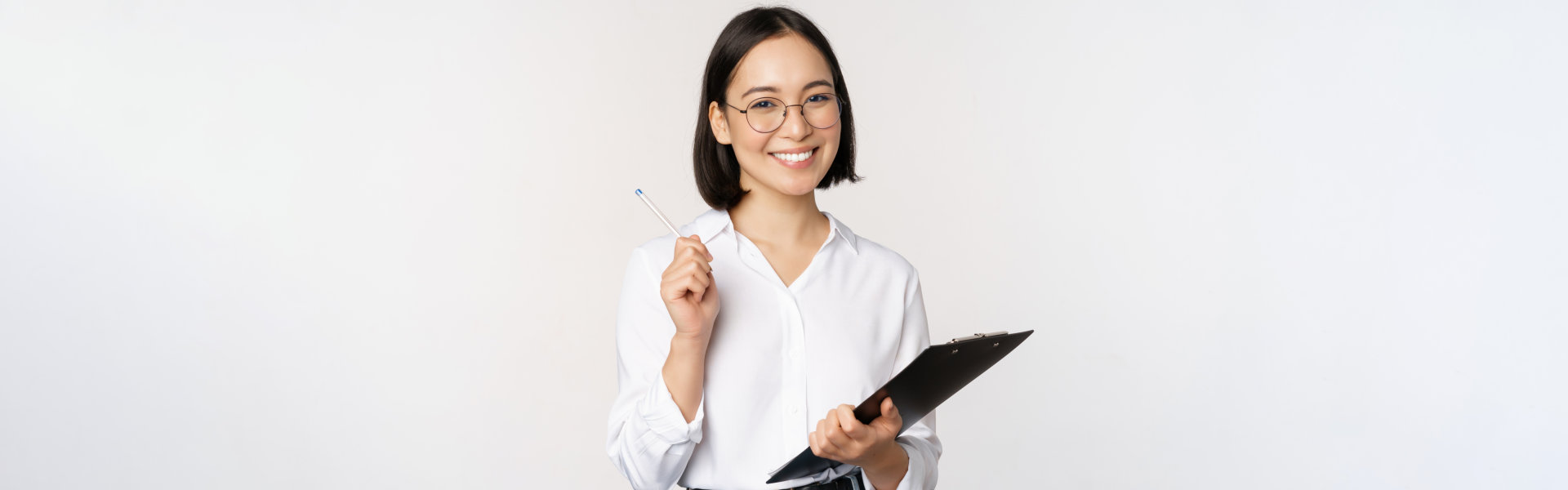 A professional woman smiling while holding a file and a pen