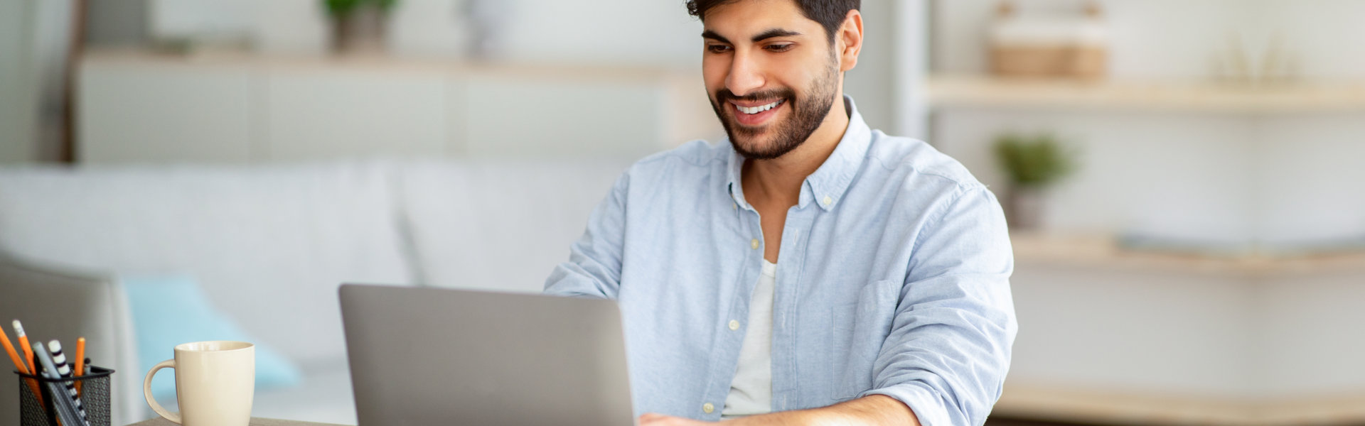 A man smiling while looking at a computer